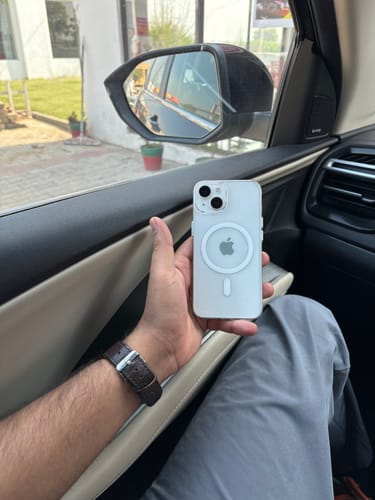 Customer holding their iPhone 14 in the white Anti Yellow Magsafe Clear Case while sitting in a car.