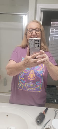 Reviewer takes a mirror selfie wearing the lavender High Altitude T-Shirt, showing its color and fit.