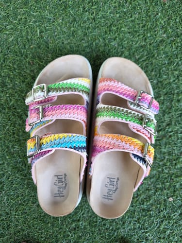 Customer's pair of Corky's sandals with colorful woven straps and buckles on a green lawn.