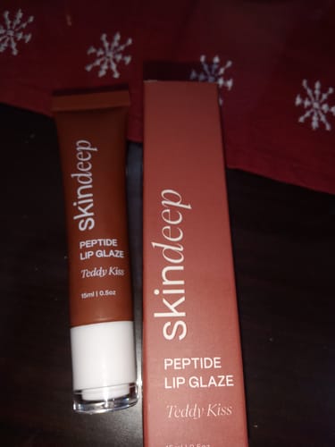 Reviewer's Peptide Lip Glaze in the brown terracotta shade Teddy Kiss, shown with its box.