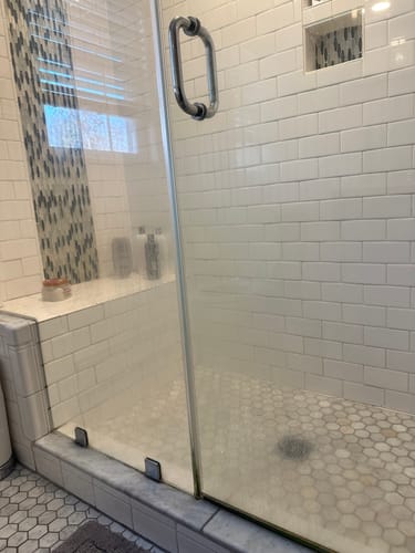 Reviewer's hazy glass shower door before being cleaned with the Bathroom Starter Bundle.