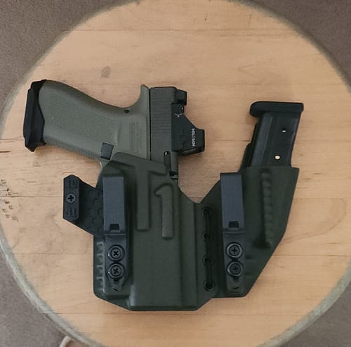 Customer's green Axis Elite holster with custom modifications, holding a pistol and an extra magazine on a wooden surface.