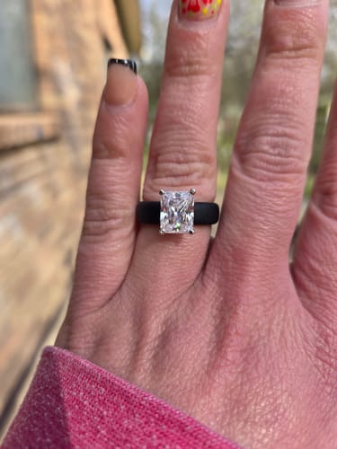 Close-up of a reviewer's hand wearing the Silicone Ring, showing the large emerald-cut stone and black band.