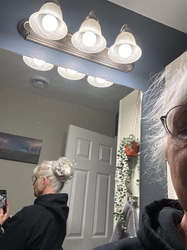Customer wearing a full, silver JuvaBun Messy Bun, seen in a mirror selfie.