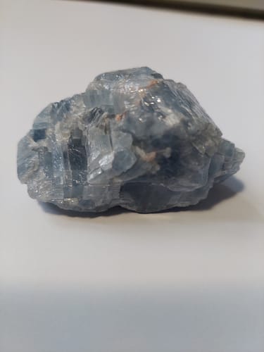 Photo d'un client montrant la pierre de calcite bleue brute non polie sur une surface unie.