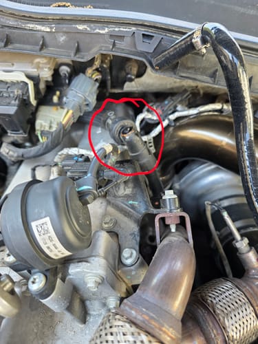 Customer photo showing a broken factory heater hose nipple in a Powerstroke engine, circled to highlight the damage.