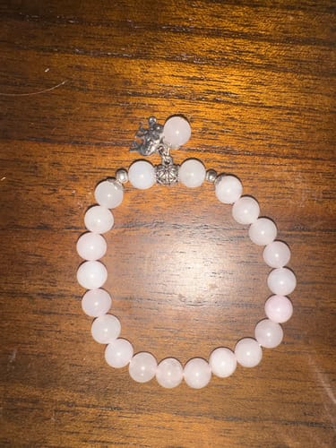 Customer's VIP Crystal Club bracelet with light pink beads and a small silver charm on a wood surface.