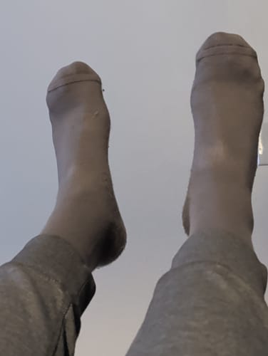 Reviewer's feet up in the air, wearing the sheer, taupe Performance Eucalyptus Compression Socks.