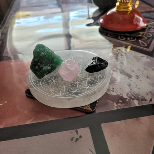 Photo d'un client montrant son Quartz Rose Brut posé sur un plateau fleur de vie avec d'autres cristaux.