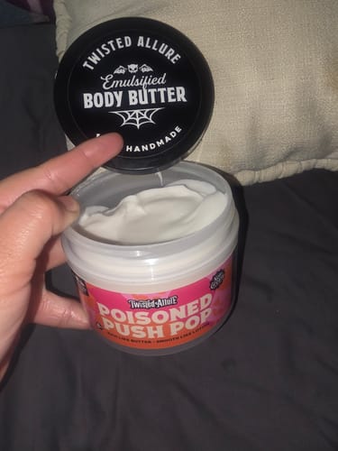 Customer holding an open jar of Poisoned Push Pop Body Butter, showing the creamy white product inside.