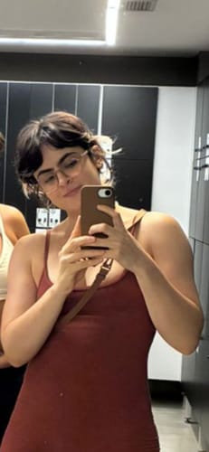 Avaliadora tira uma selfie no espelho, mostrando sua Case Mocha Mousse marrom com alça.
