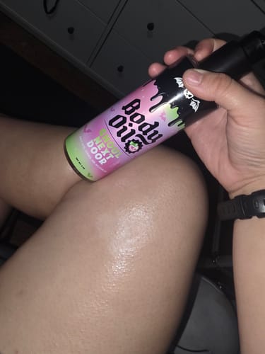 Customer holding the Ghoul Next Door Body Oil, showing the product's moisturizing glow on their leg.