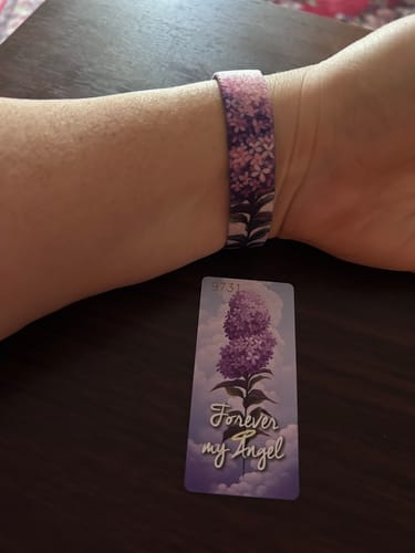 A reviewer wears the floral Forever My Angel Bracelet on their wrist, shown next to the matching inspirational card.