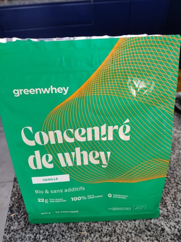 Le client montre son sachet vert de Protéine de Whey Biopro, saveur vanille, posé sur un comptoir.