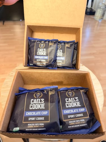 Customer shows two cardboard boxes filled with individually wrapped Cael's Chocolate Chip Cookies.