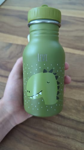 Ein Kunde hält die personalisierte grüne Trixie Trinkflasche mit Dino-Motiv und dem Namen 'Levi' in der Hand.