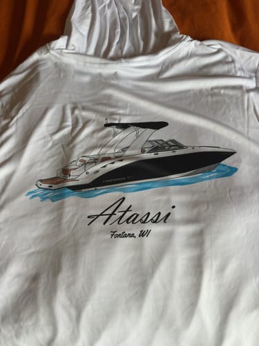 Customer's white hooded shirt showing their custom digital boat artwork of a black boat named 'Atassi'.