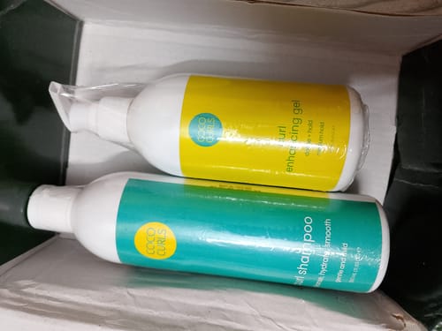 Reviewer's shrink-wrapped bottles of Curl Enhancing Gel and Curl Shampoo inside a delivery box.