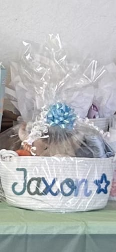 Customer's white Personalized Knitted Basket showing the name 'Jaxon' and a blue star, wrapped as a gift.