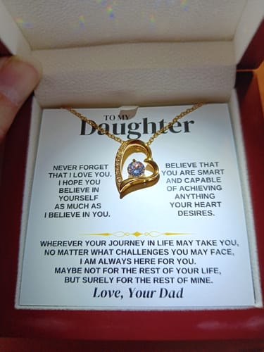 Customer holding the open 'To My Daughter' necklace gift set, showing the gold heart necklace and message card from Dad.