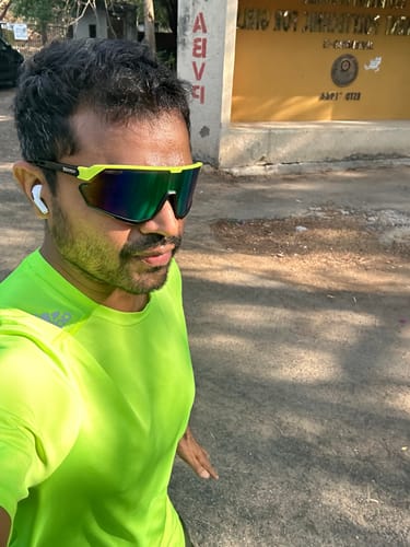 Reviewer wearing the wrap-around Voyage Select Drift Sunglasses with yellow and black frames during a run.