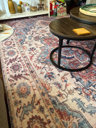 Customer's Mellow Mat Regalia rug with a classic Persian design shown in a living room next to a coffee table.