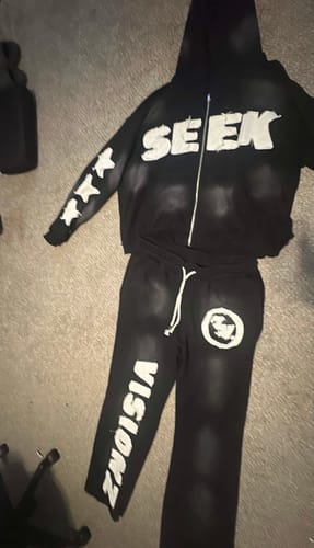 Reviewer's black SEEK VISIONZ SET hoodie and pants laid out on a floor, showing the white text and logos.