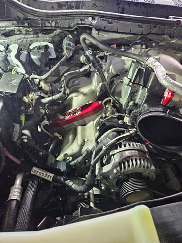 Close-up of a reviewer's red Powerstroke EGR Delete Kit installed in a truck engine bay.
