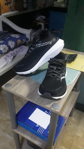 Customer's black Saucony Hurricane 24 Running Shoes with prominent white soles on a table.