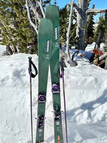 Customer's purple Marker Griffon 13 ID Ski Bindings mounted on green skis, standing upright in a snowy landscape.