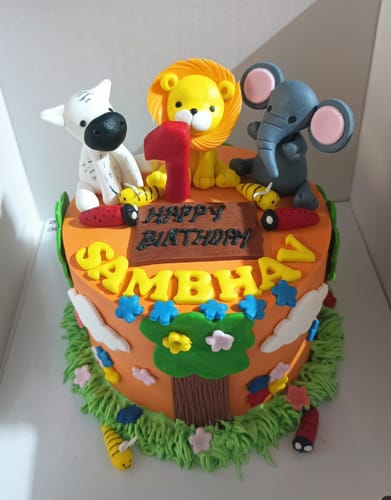 Reviewer's colorful Jungle Theme Cake with a lion, elephant, and zebra on top. A red number '1' celebrates a first birthday.