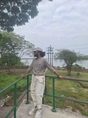 Reviewer outdoors wearing white RootsUp Yoga Pants, showing the cuffed ankle and tree embroidery.