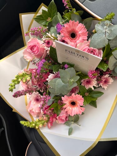 Customer's beautiful Country Garden Bouquet with pink gerberas, roses, and purple flowers, wrapped in paper.