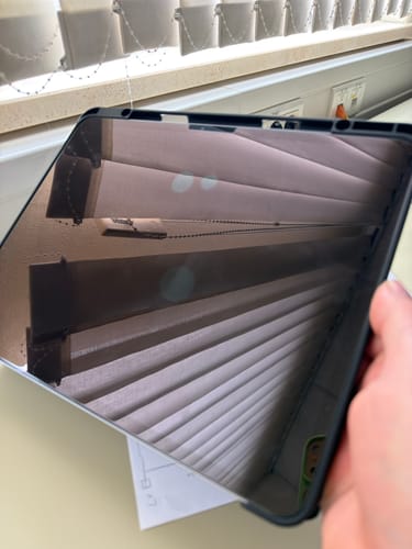 Rezensent zeigt die aufgebrachte Schutzfolie auf einem iPad, auf der drei sichtbare Blasen zu sehen sind.