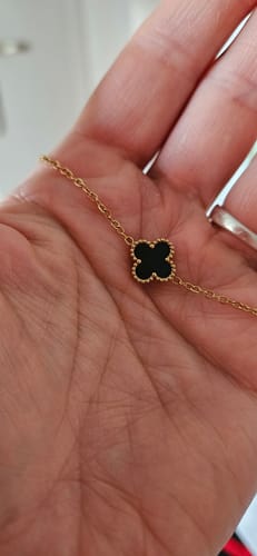 Rezensent hält das Überraschungsgeschenk, ein feines goldenes Armband mit einem schwarzen Kleeblatt-Anhänger.
