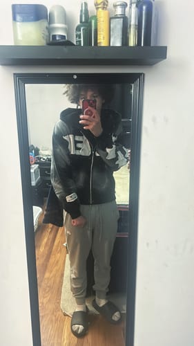 Reviewer taking a mirror selfie showing the fit of the patterned SEEK ZIPUP with grey joggers.
