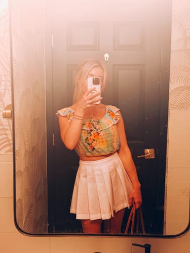 Customer wearing the structured, white Shirting Pleated Mini Skirt in a mirror selfie.