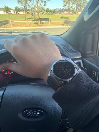 Customer wearing their Gard Pro Ultra 3 watch while driving, showing its metallic case and black band.