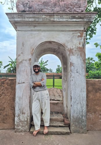 Reviewer standing in a stone archway wearing comfortable, white RootsUp Yoga Pants.