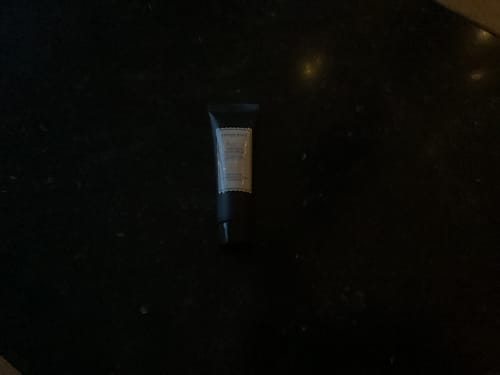 Recensent toont de tube Istanbul Handcrème op een donker oppervlak.