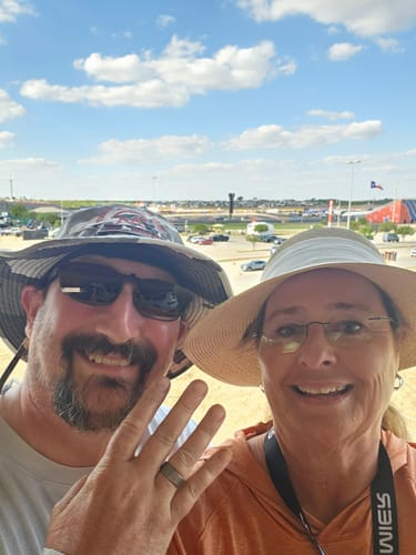 Customer showing off their Terra whiskey wood ring while smiling with their partner at an outdoor event.