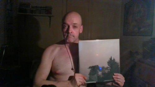 A reviewer holding up their personalized Custom Vinyl Record in a dimly lit room.