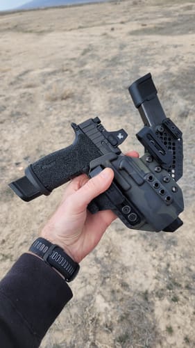 Customer holding the patterned APX holster with a handgun and an extra magazine inserted.