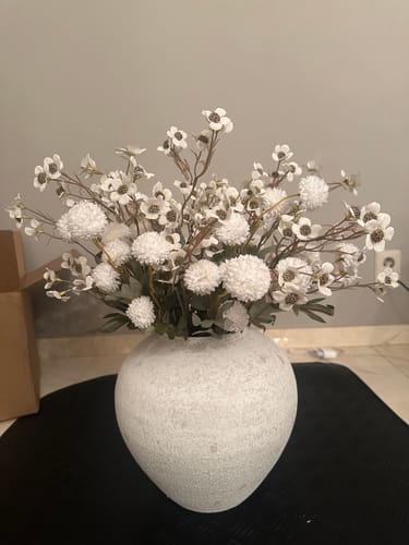 Recensent toont het witte Wax Arrangement in een grote, gespikkelde vaas.