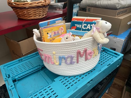 Customer's personalized white woven basket filled with books and stuffed animals.