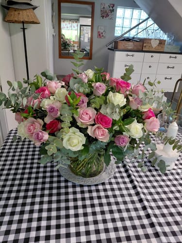 Customer's beautiful Distinctly Dreamy Bouquet with pink, white, and purple roses in a vase on a checkered table.