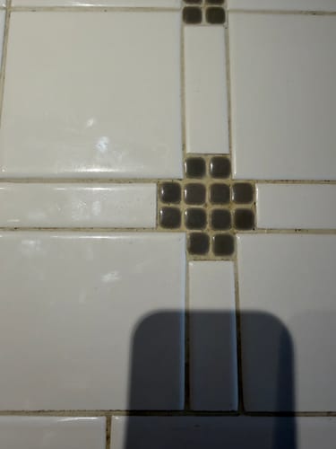 Customer shows the old, discolored grout between tiles on their kitchen island before cleaning.