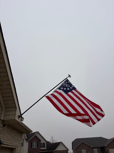 Customer's America 250™ Betsy Ross Flag waving on a flagpole against an overcast sky.