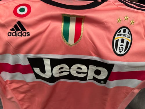 Primo piano della maglia rosa Juventus Away 2015/16 del recensore, che mostra i loghi e lo sponsor.
