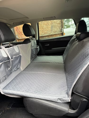 Customer's grey, quilted hammock cover installed in the back seat of a car, showing the storage pockets.